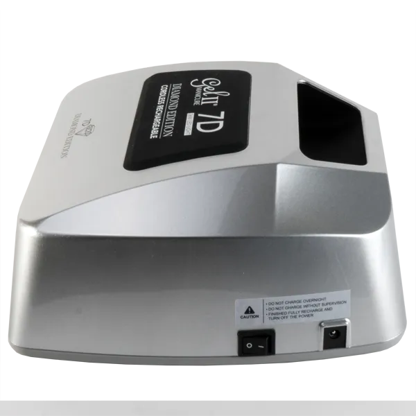A close-up of a silver electronic device with a display screen on top, labeled "Gel II Cordless Lamp 7D Diamond Edition". It shows caution and power switch labels on the front side, reminiscent of the sleek design found in the Gel II Cordless Lamp 7D Diamond Edition.