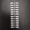 A row of white plastic spoons on a black surface for Sample Tips For Acrylic Color Chart Display Books (240pcs).
