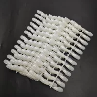 A bunch of white plastic pins on a black surface used for displaying Sample Tips For Acrylic Color Chart Display Books (240pcs).