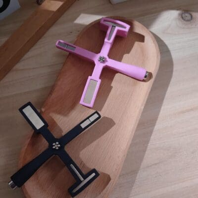 Two different-colored, Multifunctional Cat Eye Magnet Sticks lying on a wooden surface.
