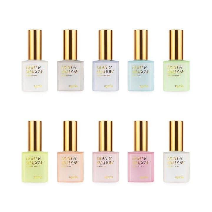 Ten bottles of Apres Light & Shadow Sheer Gel Collection 10ml with gold caps, each labeled "Light & Shadow" by Apres, displayed in two rows. They showcase a range of colors including white, yellow, blue, pink, green, and pastel shades. The collection includes Sheer Gel options for a sophisticated finish.