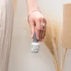 A hand holding a bottle of Gelish Soak-Off Gel Polish near a decorative vase with dried grasses, complemented by the reliable Gelish Foundation Flex Soak-Off Rubber Base Nail Gel - Clear 15ML for perfect nails.
